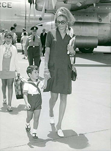 Foto vintage de Farah Pahlavi andando no aeroporto com o filho.