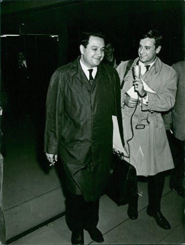 Foto vintage de Mehdi Ben Barka conversando com um homem enquanto caminha.